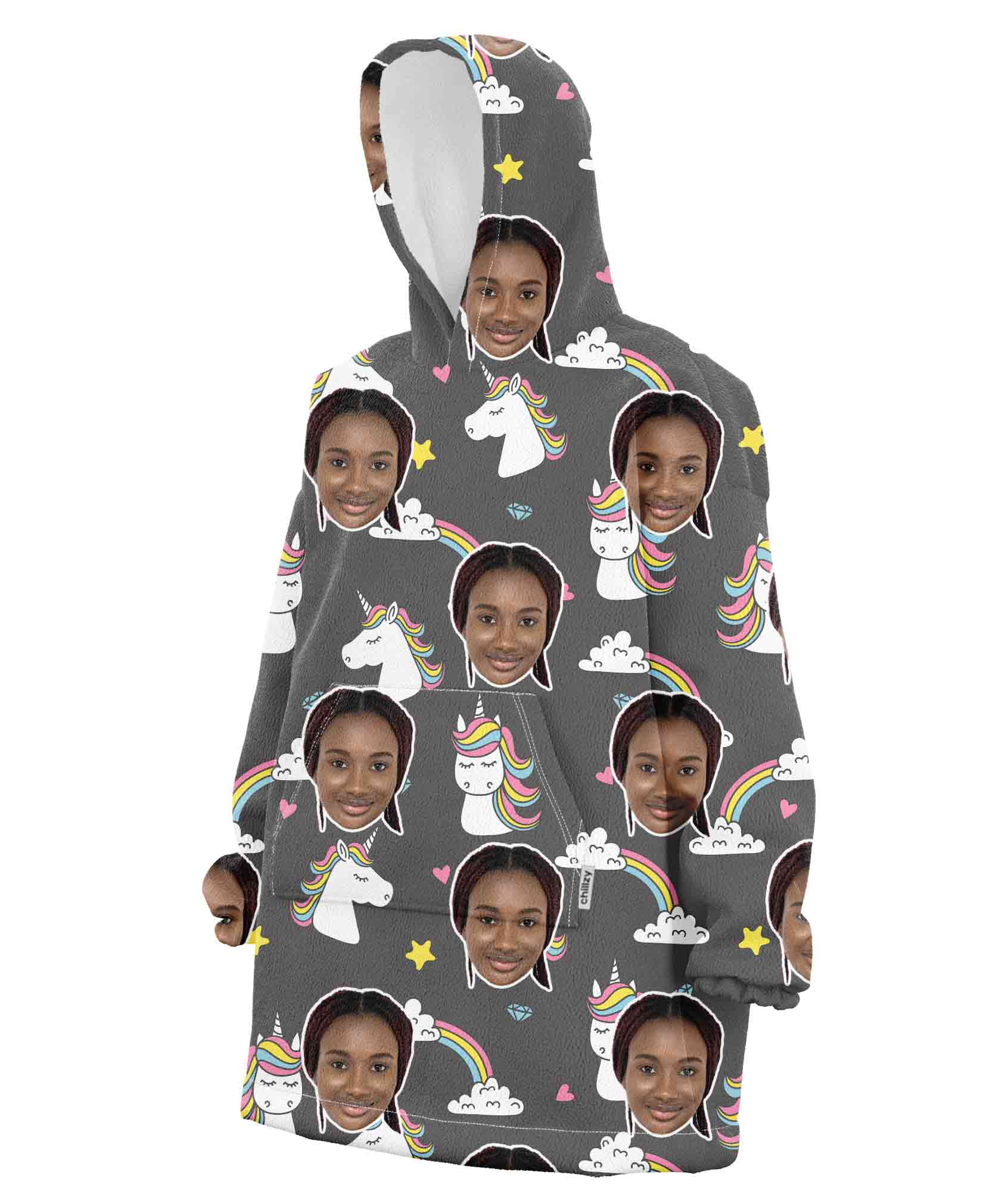 A pink hooded blanket with a pattern of a person's face and cartoonish unicorns and rainbows.