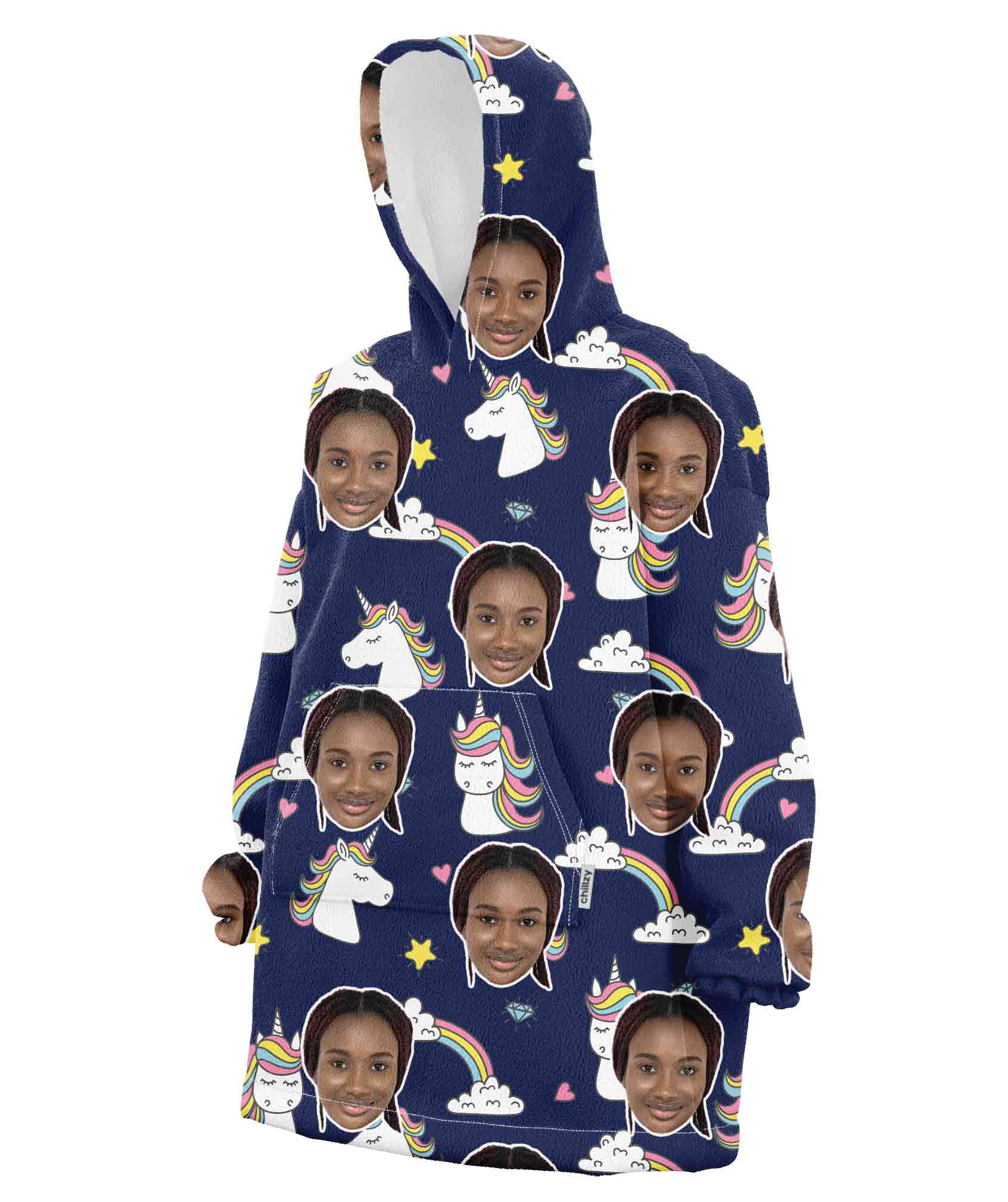 A pink hooded blanket with a pattern of a person's face and cartoonish unicorns and rainbows.
